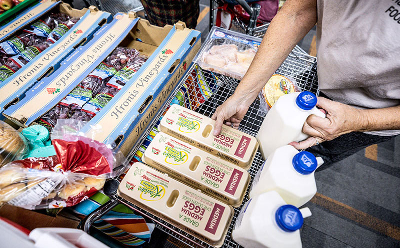 Food Distribution at Harrisburg Area Pantry Person placing groceries including eggs and milk into a cart at a food distribution site